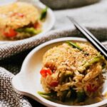 fried rice on a white plate with chopsticks on top