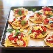 A tray of tostadas with vegetables and herbs on it.