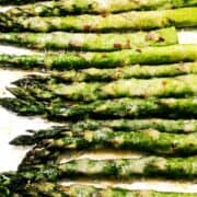 Roasted asparagus with melted cheese on top on a sheet pan.
