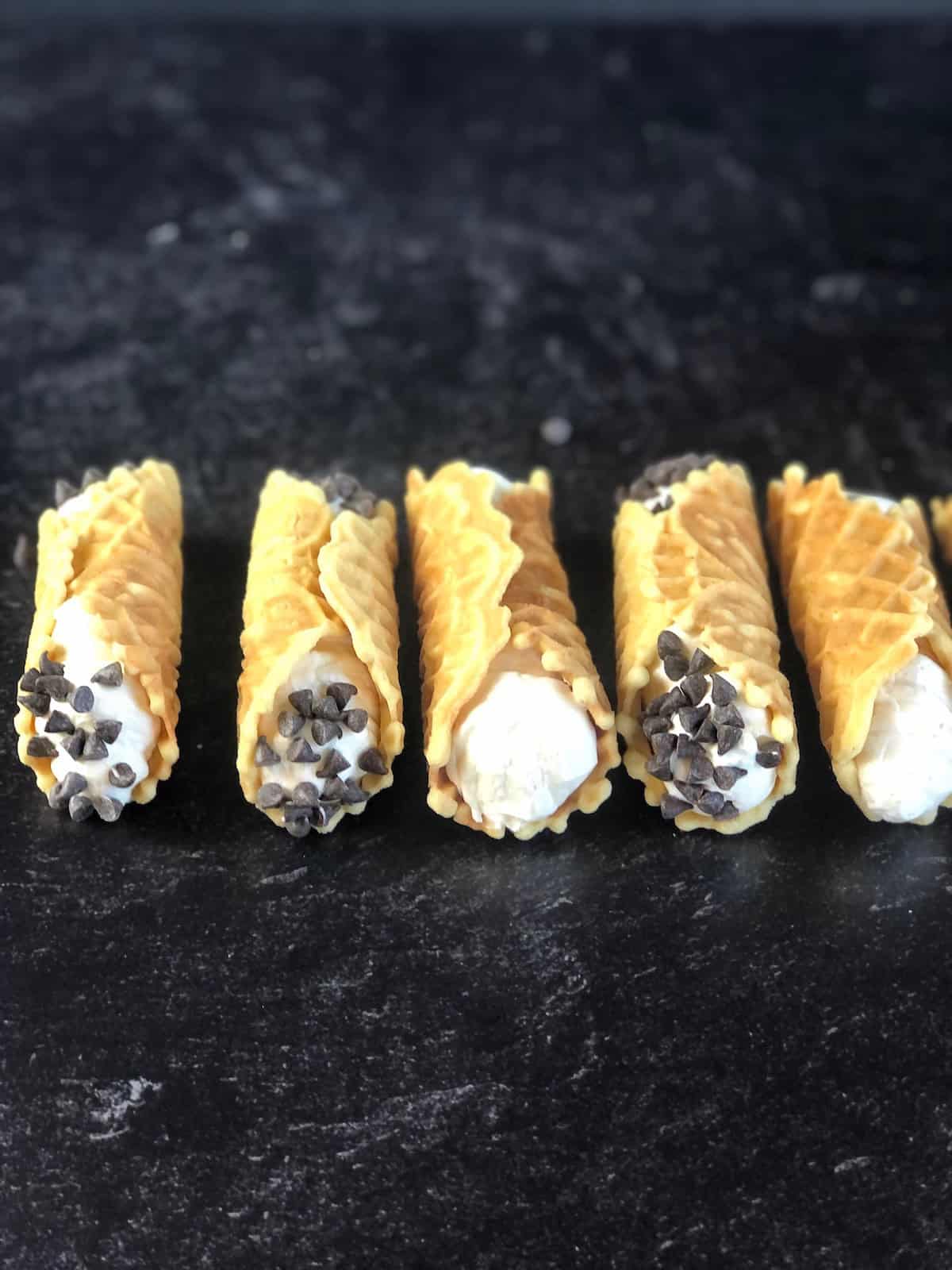Pizzelle cannoli on a black counter.
