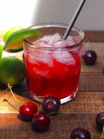 Homemade cherry limeade in a glass with ice.