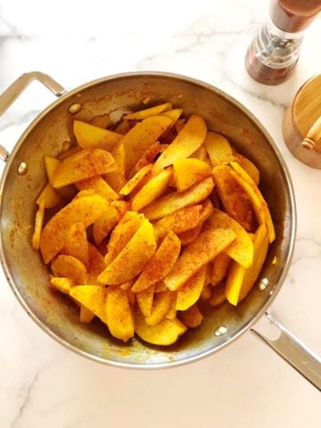 Golden potatoes with turmeric in a large saute pan.