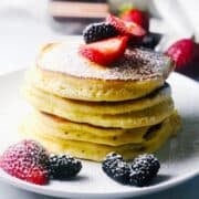 A stack of ricotta pancakes on a plate with fresh berries.