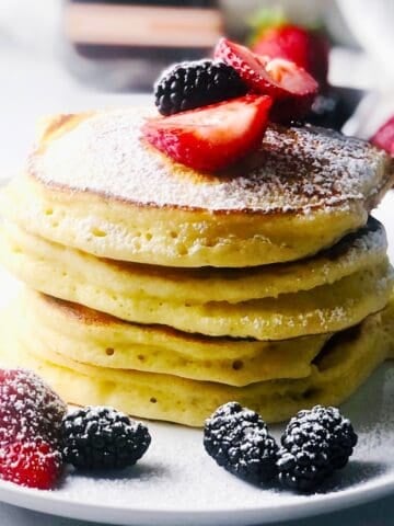 A stack of ricotta pancakes on a plate with fresh berries.