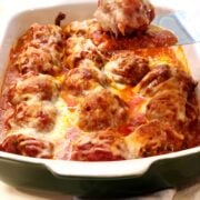 Baked meatball Parmesan with a spatula scooping out the meatballs.
