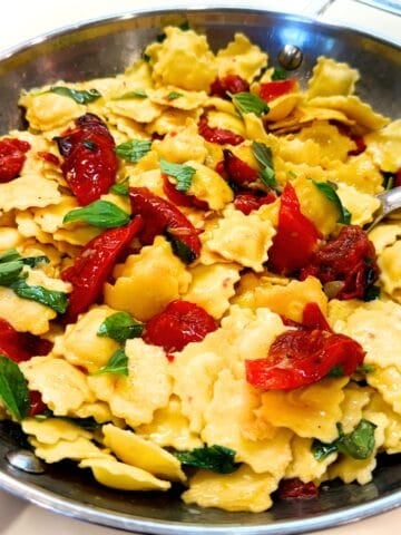 Roasted tomato and raviolini pasta in a large pan.